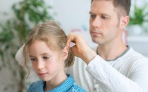 Father checking daughers hair for lice and nits