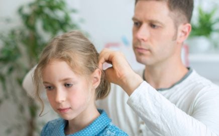 Father checking daughers hair for lice and nits