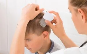 Mom using lice comb to remove hair from boys head