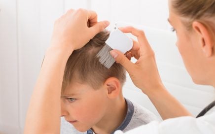 Mom using lice comb to remove hair from boys head