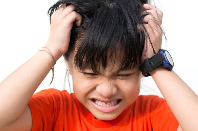 young girl holding hair as if she's itchy