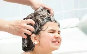 4 year old girl getting her hair washed with soap in the bath tub